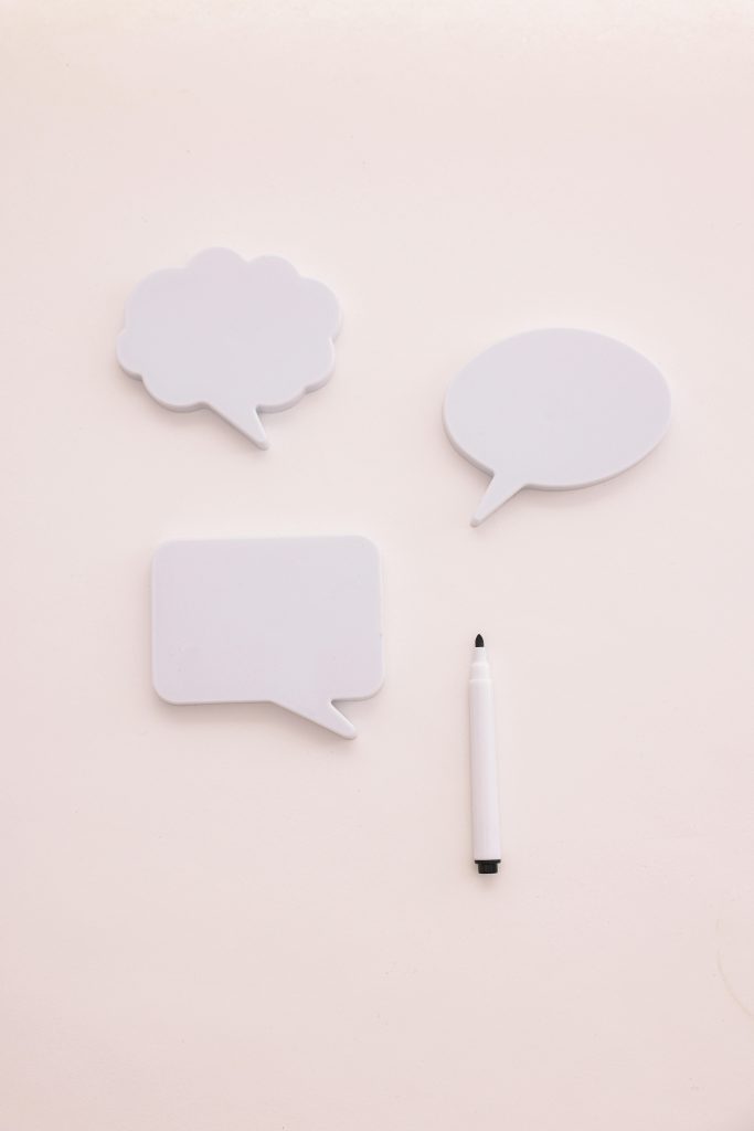 A whiteboard marker pen and three speech bubble shaped post it notes, one circular, one square, and one cloud shaped